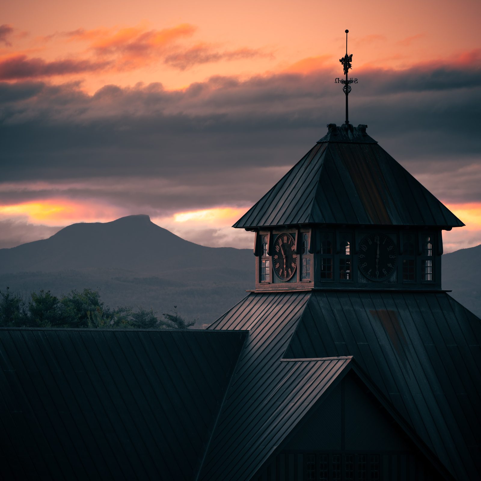 Silhouette of the Farm Barn clock tower at sunset, with Camel's Hump on the horizon